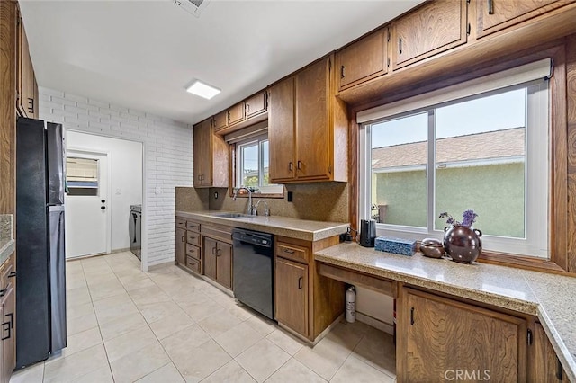 kitchen featuring light tile patterned flooring, sink, brick wall, decorative backsplash, and black appliances