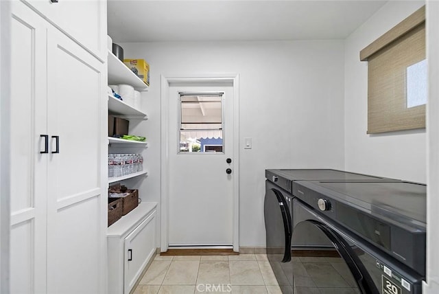 clothes washing area with light tile patterned floors and washer and clothes dryer