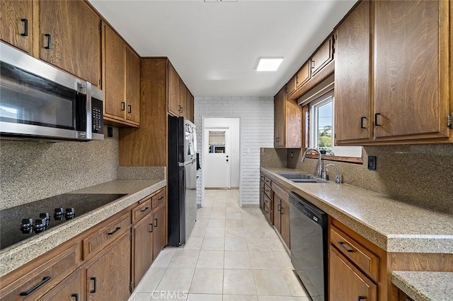 kitchen featuring sink, light tile patterned floors, black appliances, and decorative backsplash