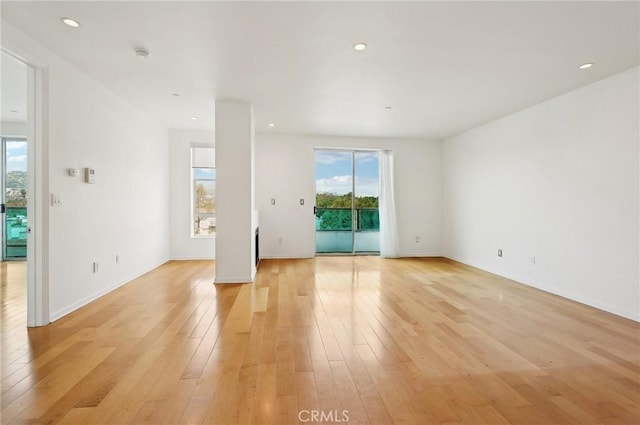 spare room featuring a healthy amount of sunlight and light hardwood / wood-style floors