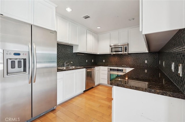 kitchen with sink, dark stone counters, white cabinets, and appliances with stainless steel finishes