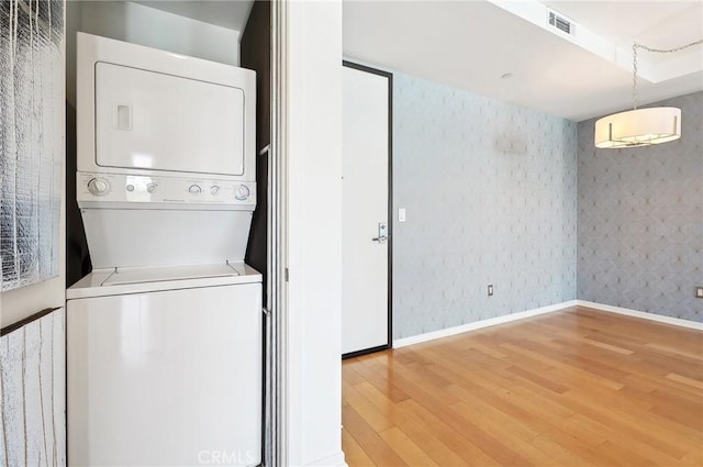 washroom with hardwood / wood-style flooring and stacked washer / dryer