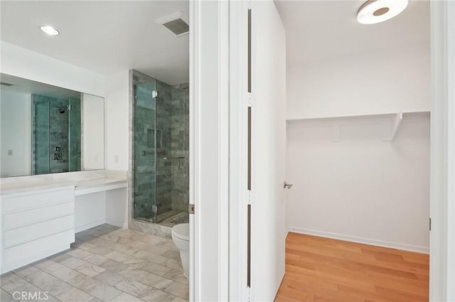 bathroom featuring vanity, hardwood / wood-style floors, a shower with shower door, and toilet