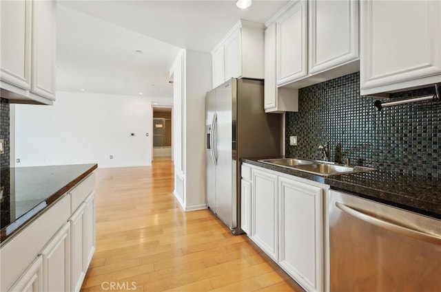 kitchen featuring white cabinetry, stainless steel appliances, sink, and dark stone counters