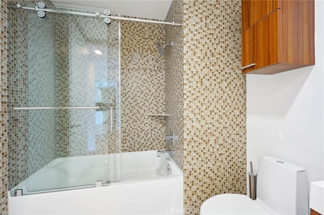 bathroom featuring combined bath / shower with glass door and toilet