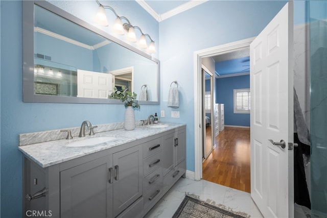 bathroom featuring marble finish floor, ornamental molding, a sink, and visible vents