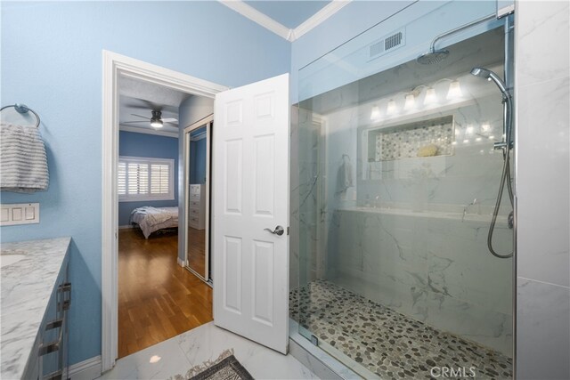 bathroom featuring ornamental molding, tiled shower, and vanity