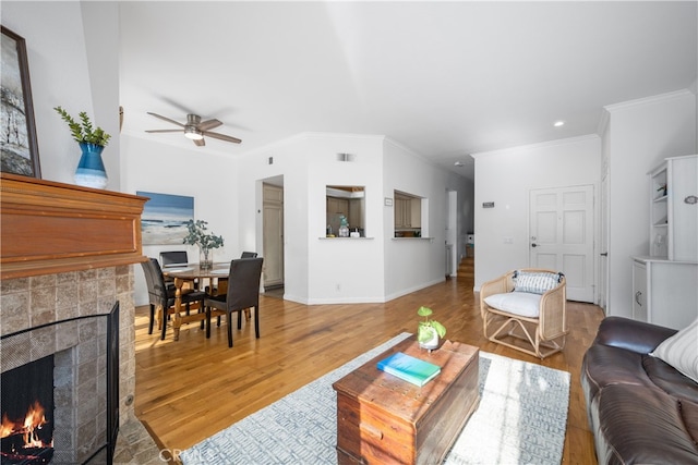 living room featuring crown molding, hardwood / wood-style flooring, a fireplace, and ceiling fan