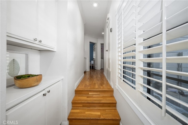 hall featuring light wood-type flooring, baseboards, ornamental molding, and recessed lighting