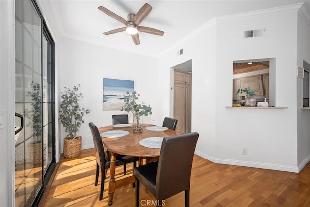 dining room featuring baseboards, crown molding, visible vents, and wood finished floors