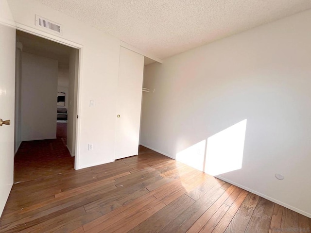 spare room with dark hardwood / wood-style flooring and a textured ceiling