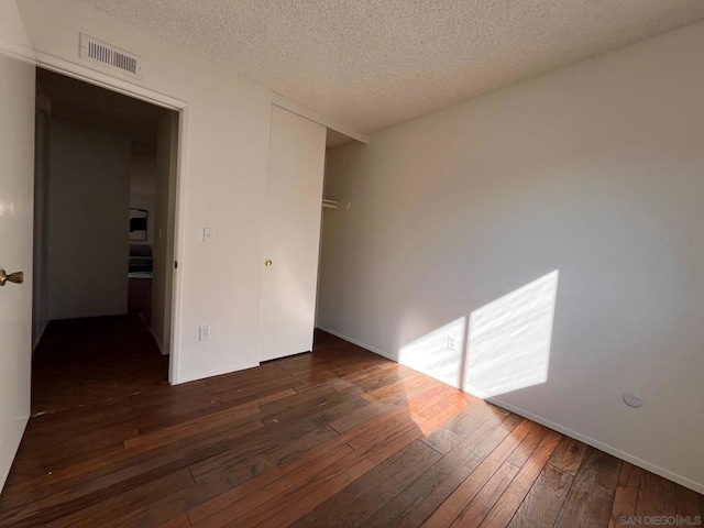 unfurnished room featuring dark wood-type flooring and a textured ceiling