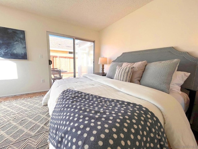 bedroom with hardwood / wood-style flooring, access to exterior, and a textured ceiling