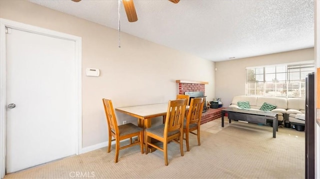 dining area featuring light carpet, a textured ceiling, a fireplace, and ceiling fan