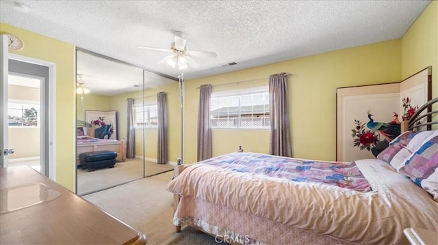 bedroom featuring ceiling fan, light carpet, a closet, and a textured ceiling