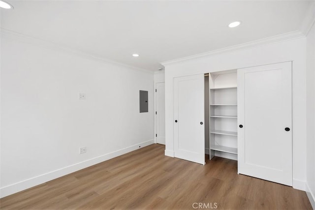 unfurnished bedroom with hardwood / wood-style flooring, ornamental molding, electric panel, and a closet