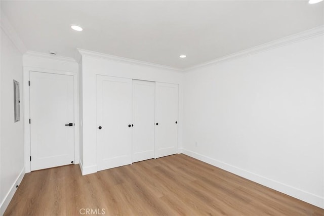 unfurnished bedroom featuring crown molding, a closet, and light hardwood / wood-style flooring