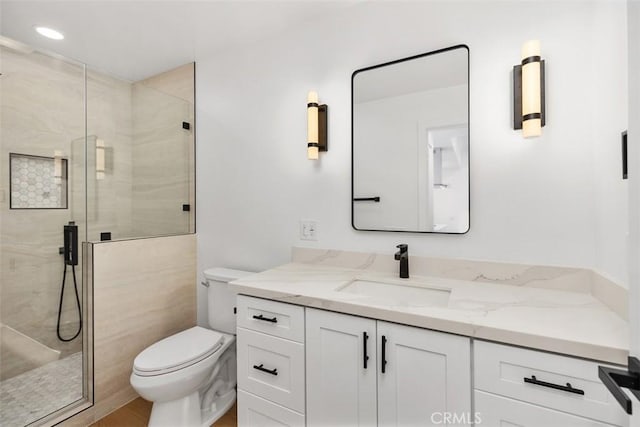 bathroom featuring vanity, toilet, and a shower with shower door