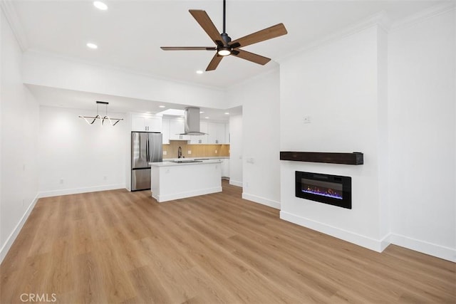 unfurnished living room with sink, ornamental molding, light hardwood / wood-style floors, and ceiling fan