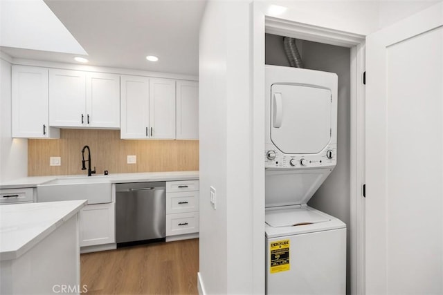 clothes washing area featuring stacked washer / dryer, light hardwood / wood-style floors, and sink