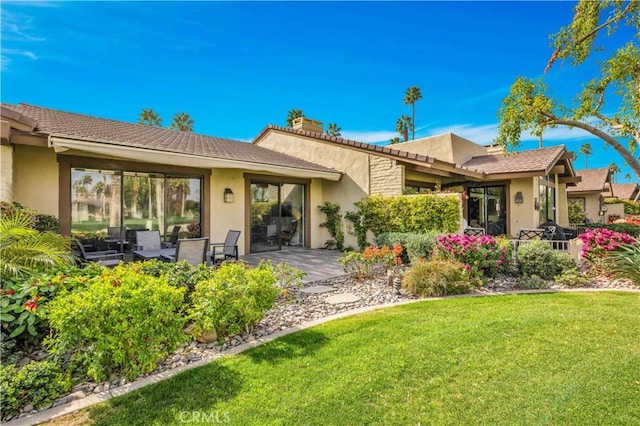 rear view of house with a patio and a yard