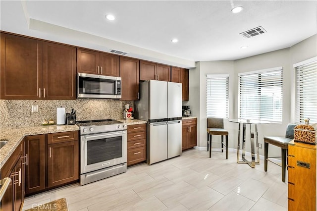 kitchen with light stone counters, appliances with stainless steel finishes, and tasteful backsplash