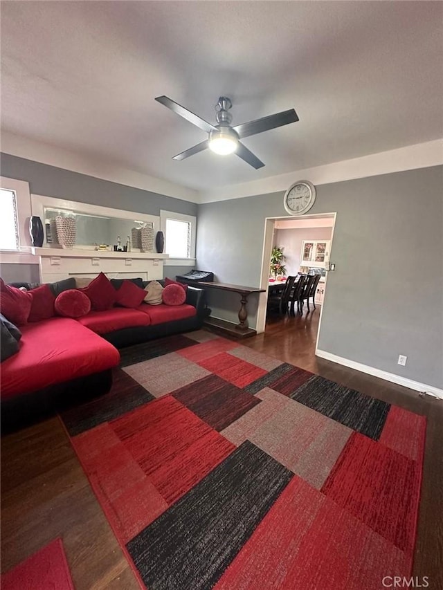 living room with dark wood-style flooring, ceiling fan, and baseboards