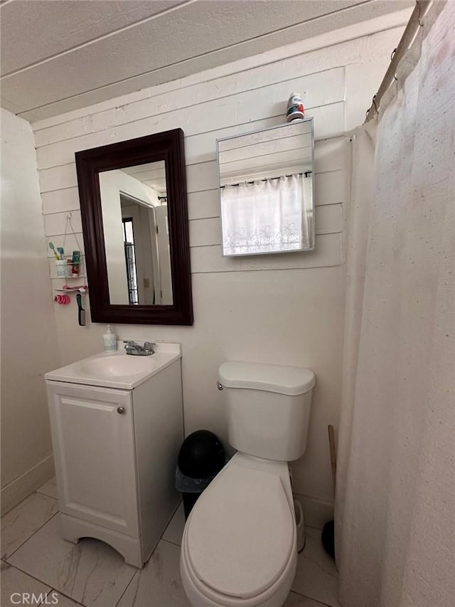 full bathroom featuring toilet, wood walls, and vanity