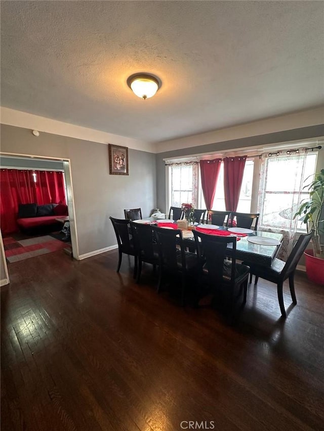 dining area featuring dark wood-style floors, baseboards, and a textured ceiling