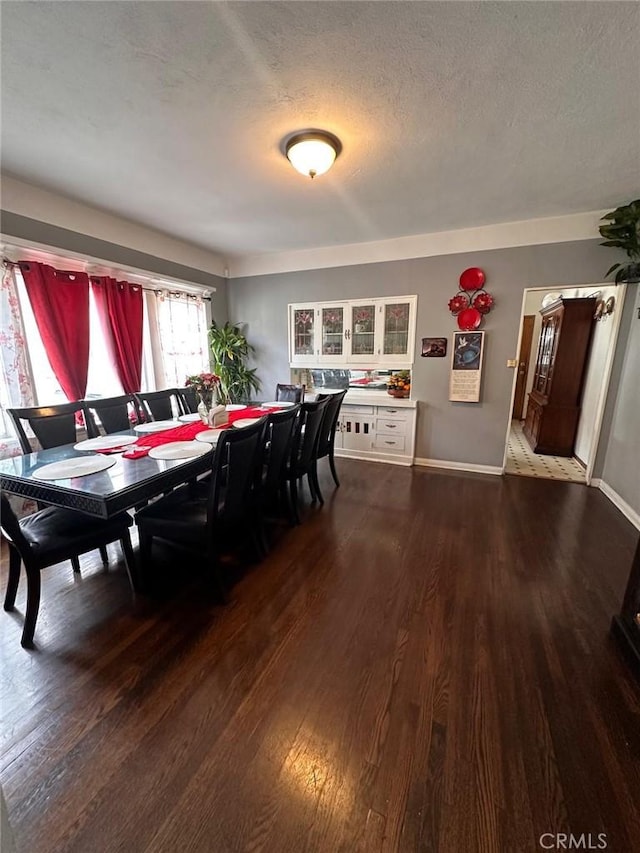 dining room featuring a textured ceiling, baseboards, and wood finished floors