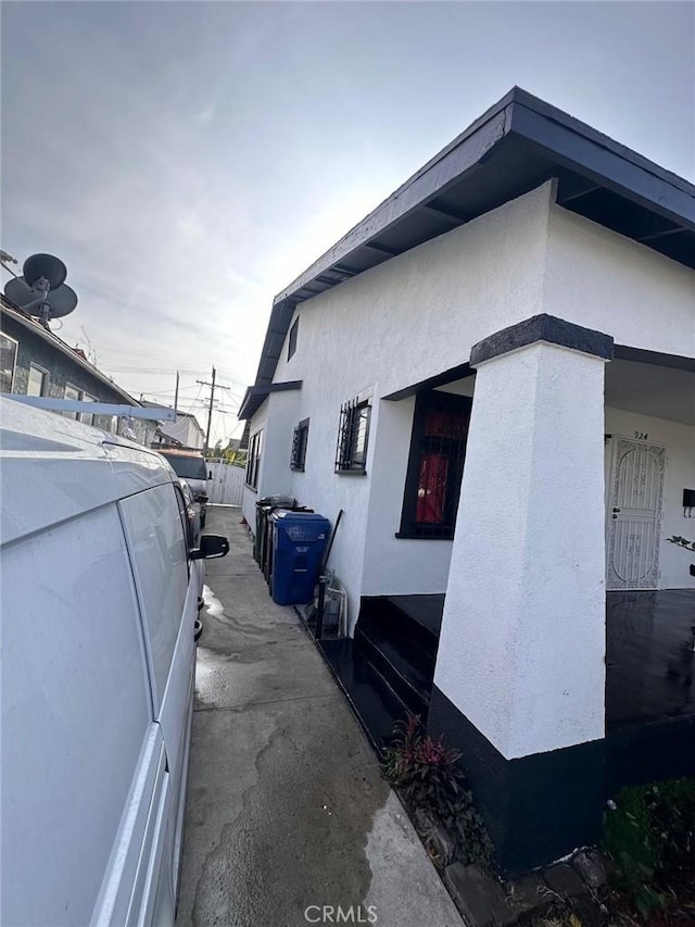 view of side of home featuring fence and stucco siding