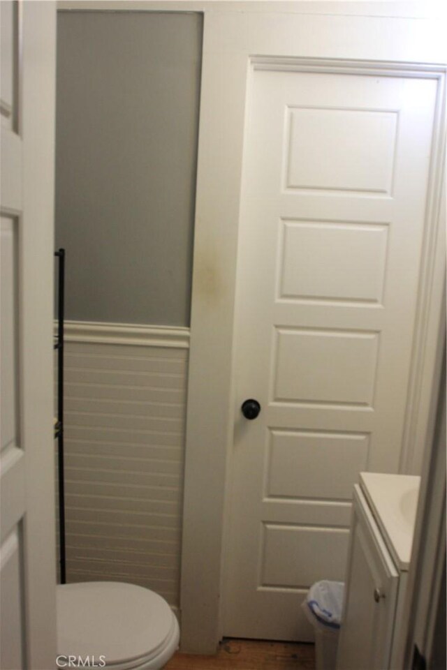 bathroom featuring wainscoting, vanity, toilet, and wood finished floors