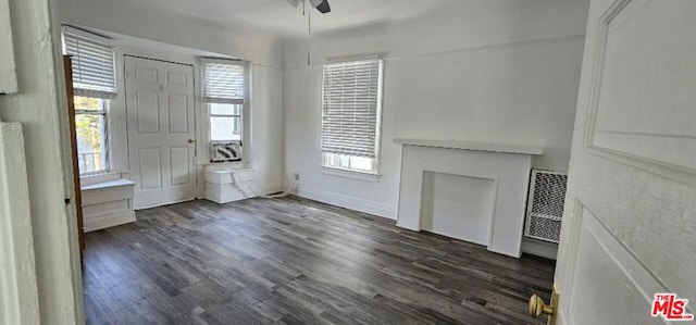 unfurnished living room with dark hardwood / wood-style floors and ceiling fan