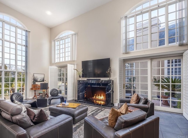 living room with tile patterned floors, a premium fireplace, and a high ceiling