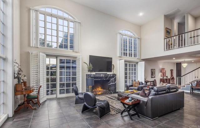 tiled living room featuring a high end fireplace and a high ceiling