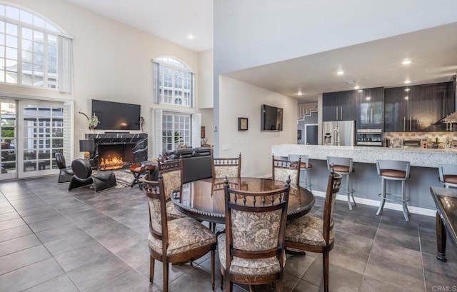 tiled dining area with a premium fireplace and a towering ceiling