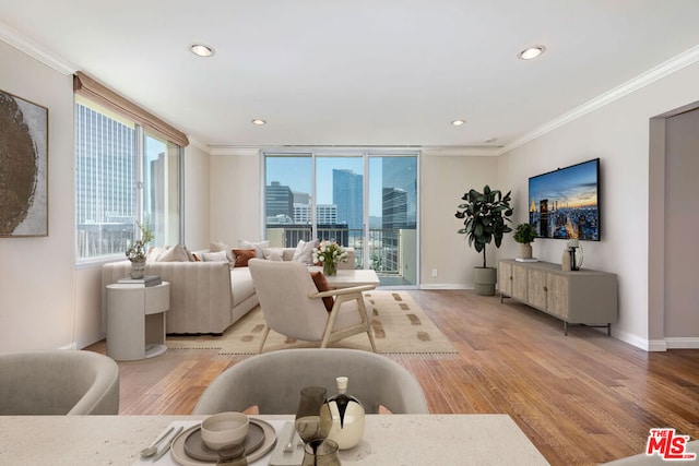 living room featuring crown molding, a healthy amount of sunlight, and light wood-type flooring