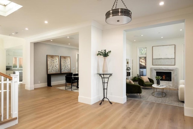 interior space featuring a skylight, crown molding, a fireplace, and light wood-type flooring