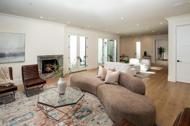 living room with crown molding, a premium fireplace, hardwood / wood-style floors, and french doors