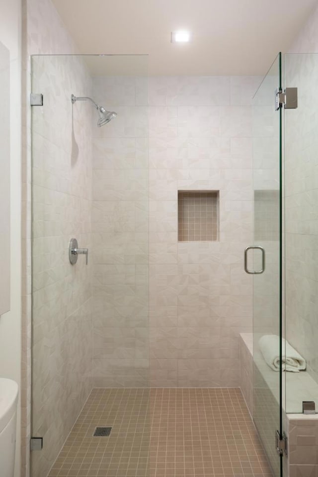 bathroom with a shower with door and toilet