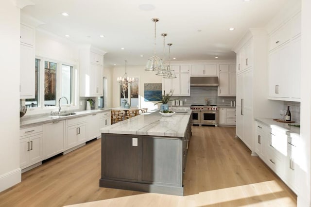 kitchen with pendant lighting, double oven range, white cabinetry, and a kitchen island