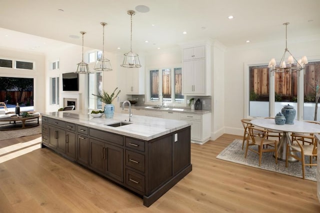 kitchen with light stone counters, sink, decorative light fixtures, and white cabinets