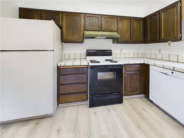 kitchen with dark brown cabinetry, tile counters, white appliances, and light hardwood / wood-style flooring