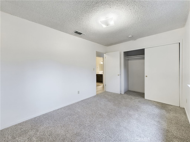 unfurnished bedroom featuring light colored carpet, a closet, and a textured ceiling