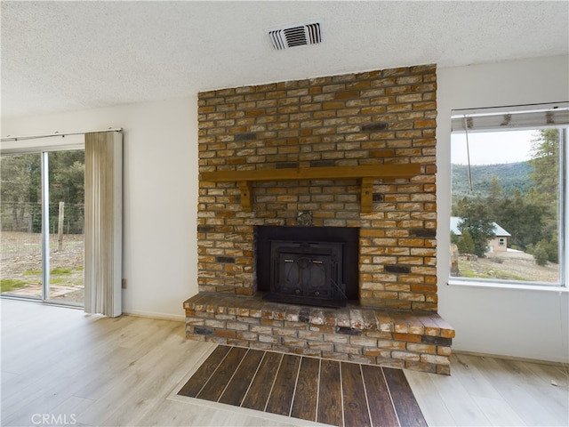 details featuring hardwood / wood-style flooring, a brick fireplace, and a textured ceiling