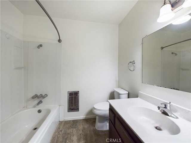 full bathroom featuring hardwood / wood-style flooring, washtub / shower combination, heating unit, vanity, and toilet