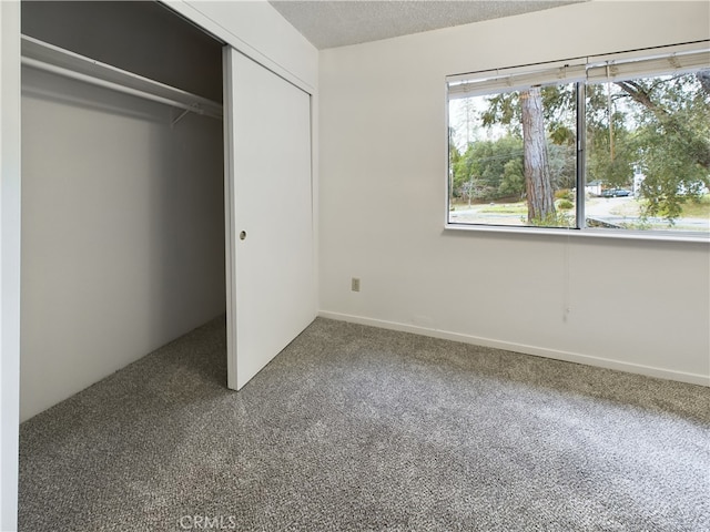 unfurnished bedroom featuring carpet floors, a textured ceiling, and a closet