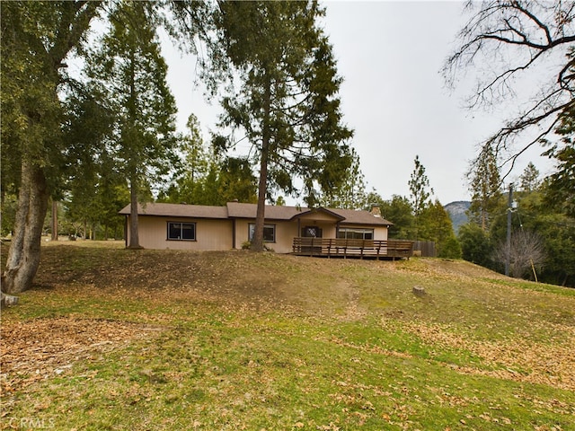 rear view of property with a wooden deck and a lawn