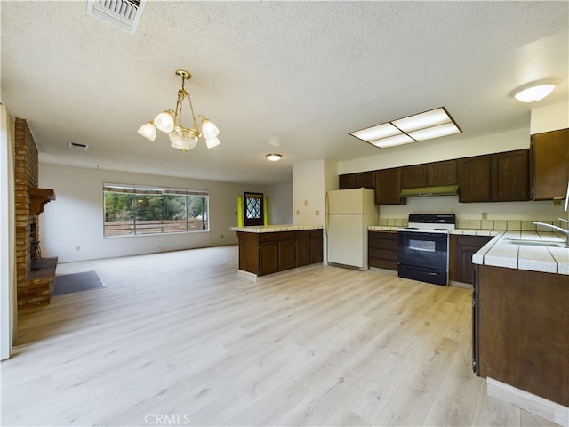 kitchen with sink, decorative light fixtures, dark brown cabinets, white refrigerator, and range with electric cooktop