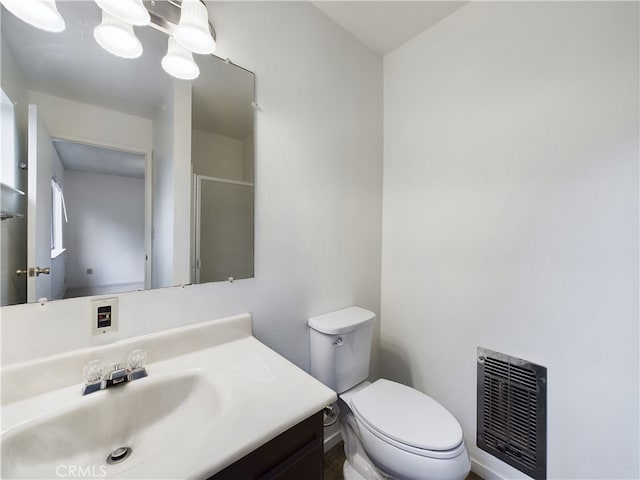 bathroom featuring walk in shower, vanity, toilet, and heating unit